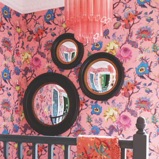 thre distorted black circular mirrors on bright pink patterend wallpaper. On a stairwell