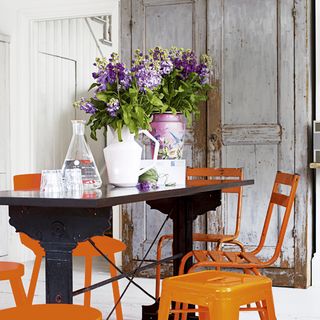 grey and white dining room with orange metal chairs