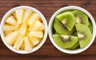 A bowl of fresh pineapple and a bowl of fresh kiwi fruit