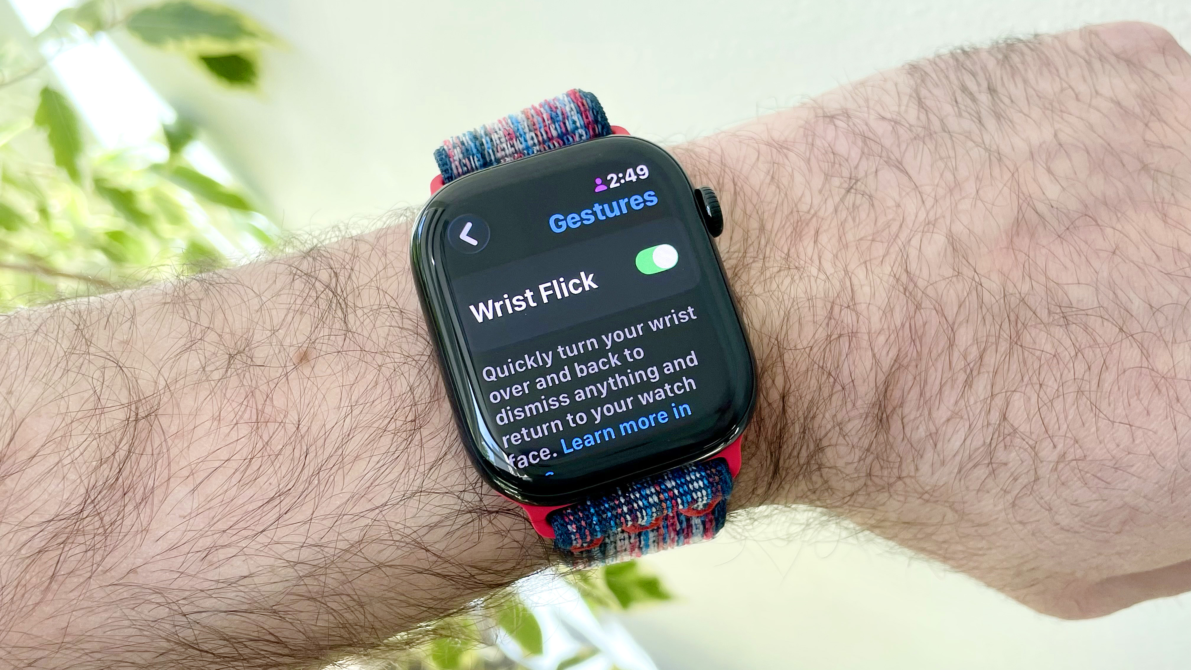 Close-up of an Apple Watch 10 on a user's wrist showing the menu option to turn on the new Wrist Flick gesture in watchOS 26