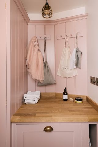 small pink laundry room with wall hooks by deVOL