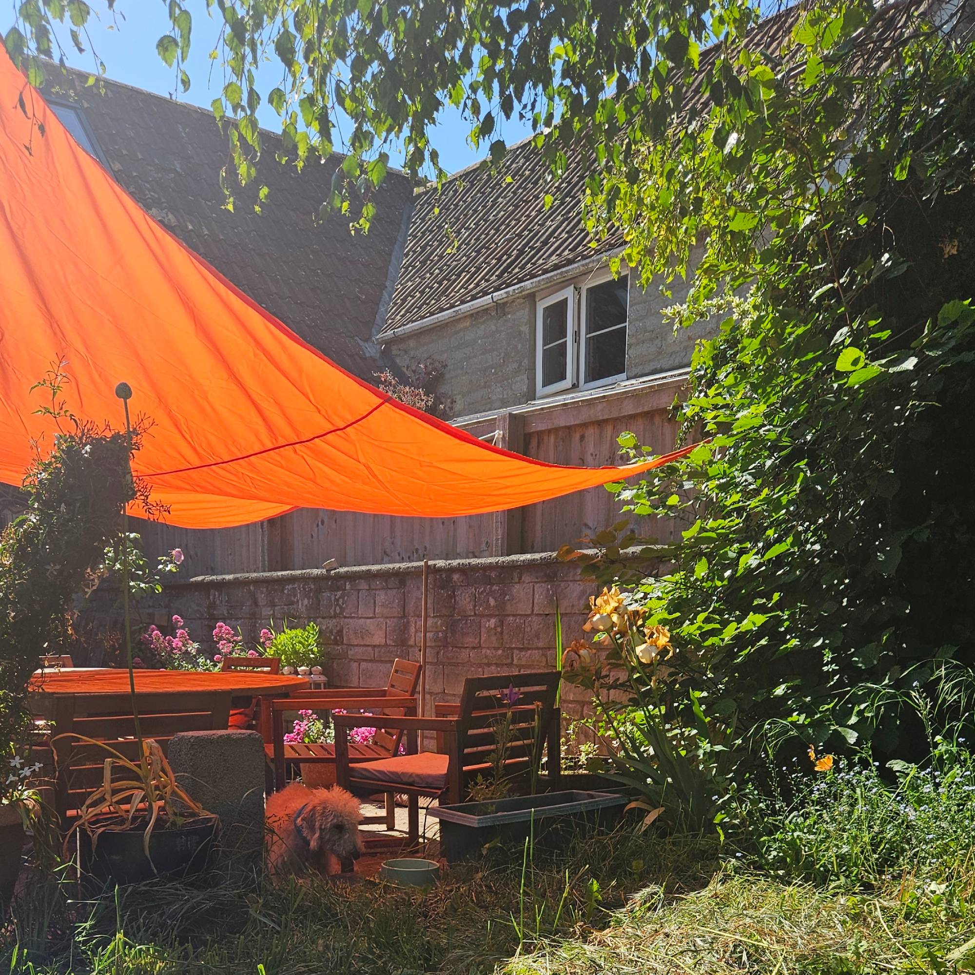orange sail shade above courtyard garden with wooden table