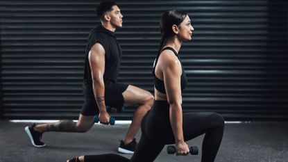 A man and woman perform dumbbell lunges simultaneously