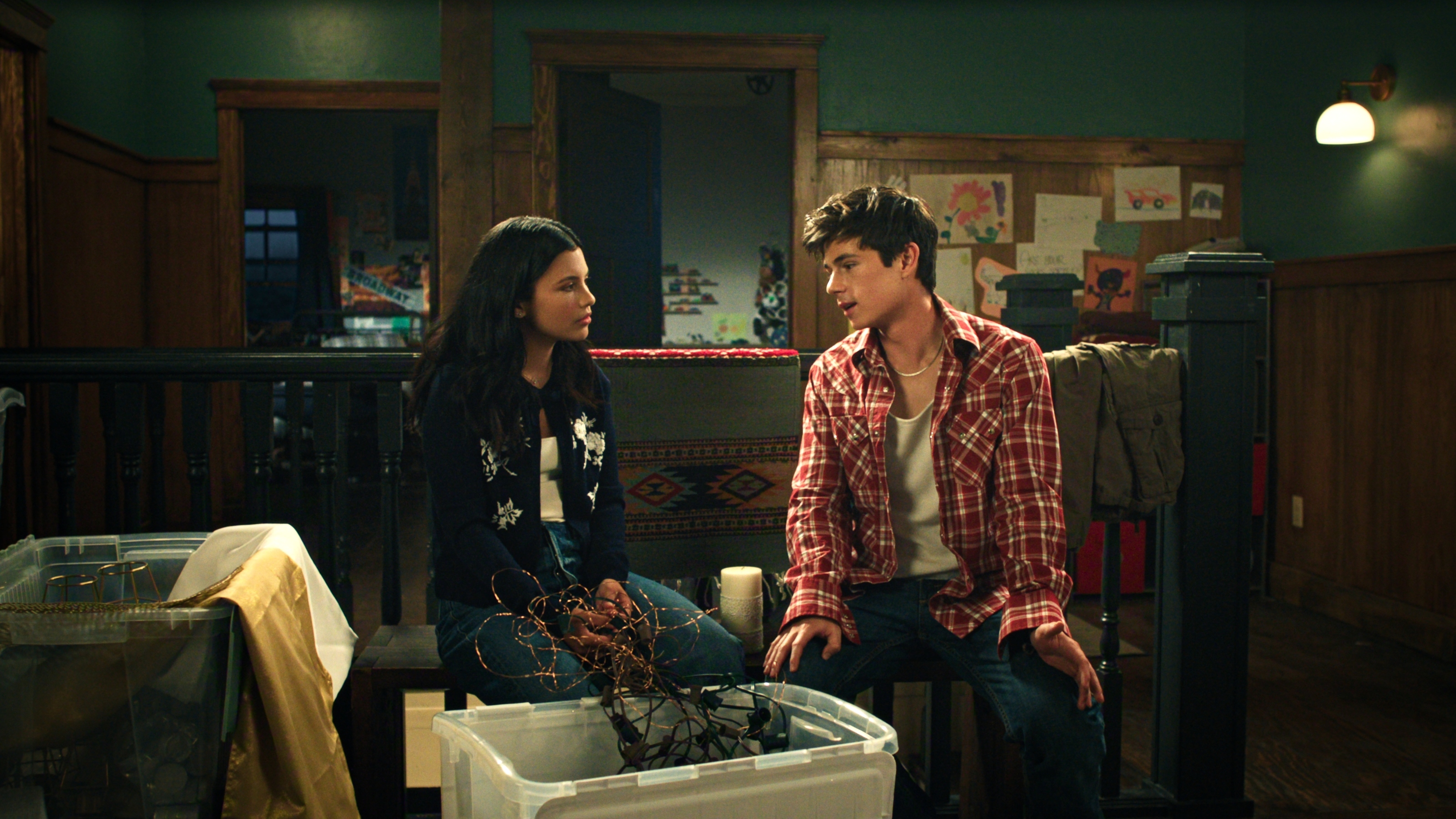 Nikki Rodriguez as Jackie Howard and Ashby Gentry as Alex Walter sitting with each other with plastic boxes around them.