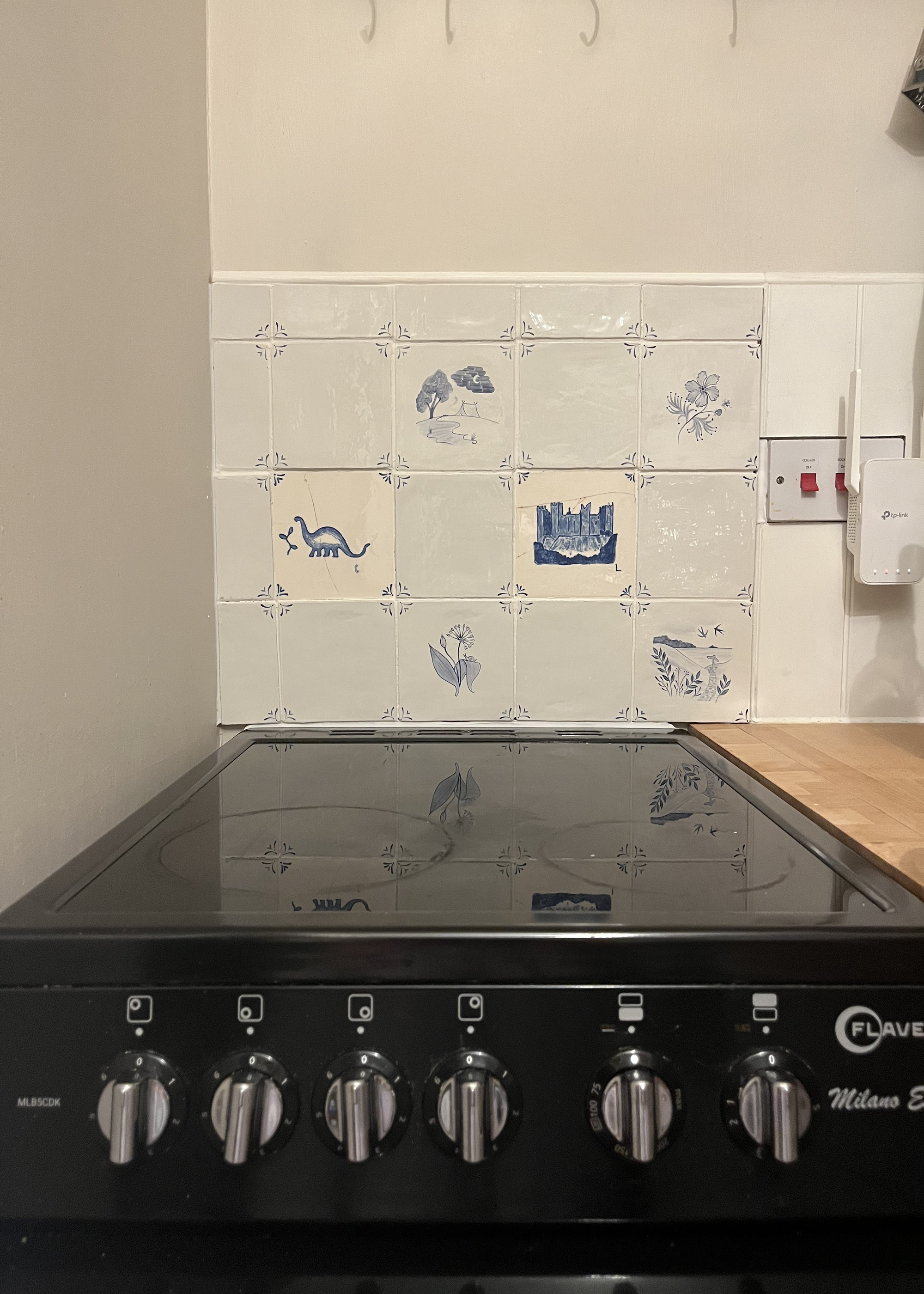 A kitchen with a black oven and a backsplash featuring Delft tiles