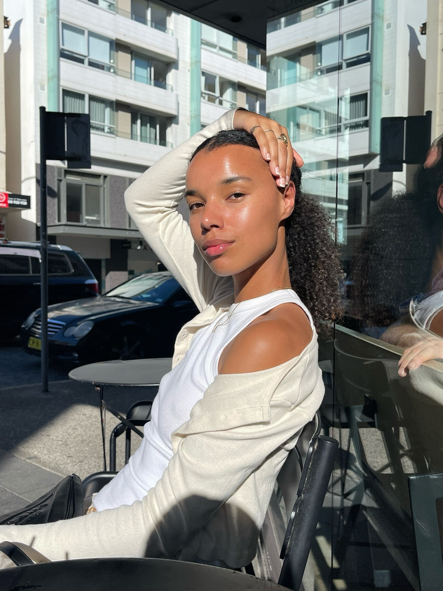 A woman sitting in the sun with a middle-parted ponytail hairstyle