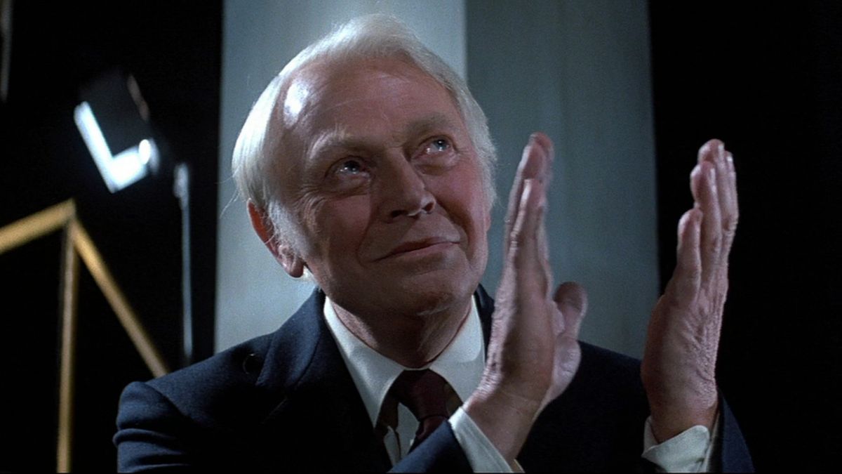 Dan O&#039;Herlihy looks up and claps in dark glee in Halloween III: Season of the Witch. 