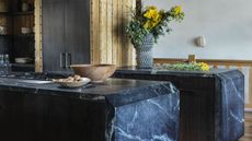 Kitchen countertops with soapstone used on both counters. On one countertop there is also a stove with two bowls and on the other is a vase with flowers inside of it 