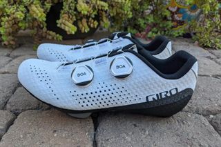 Giro Regime Women's Road Cycling Shoes are pictured in white in a pair on paved ground.
