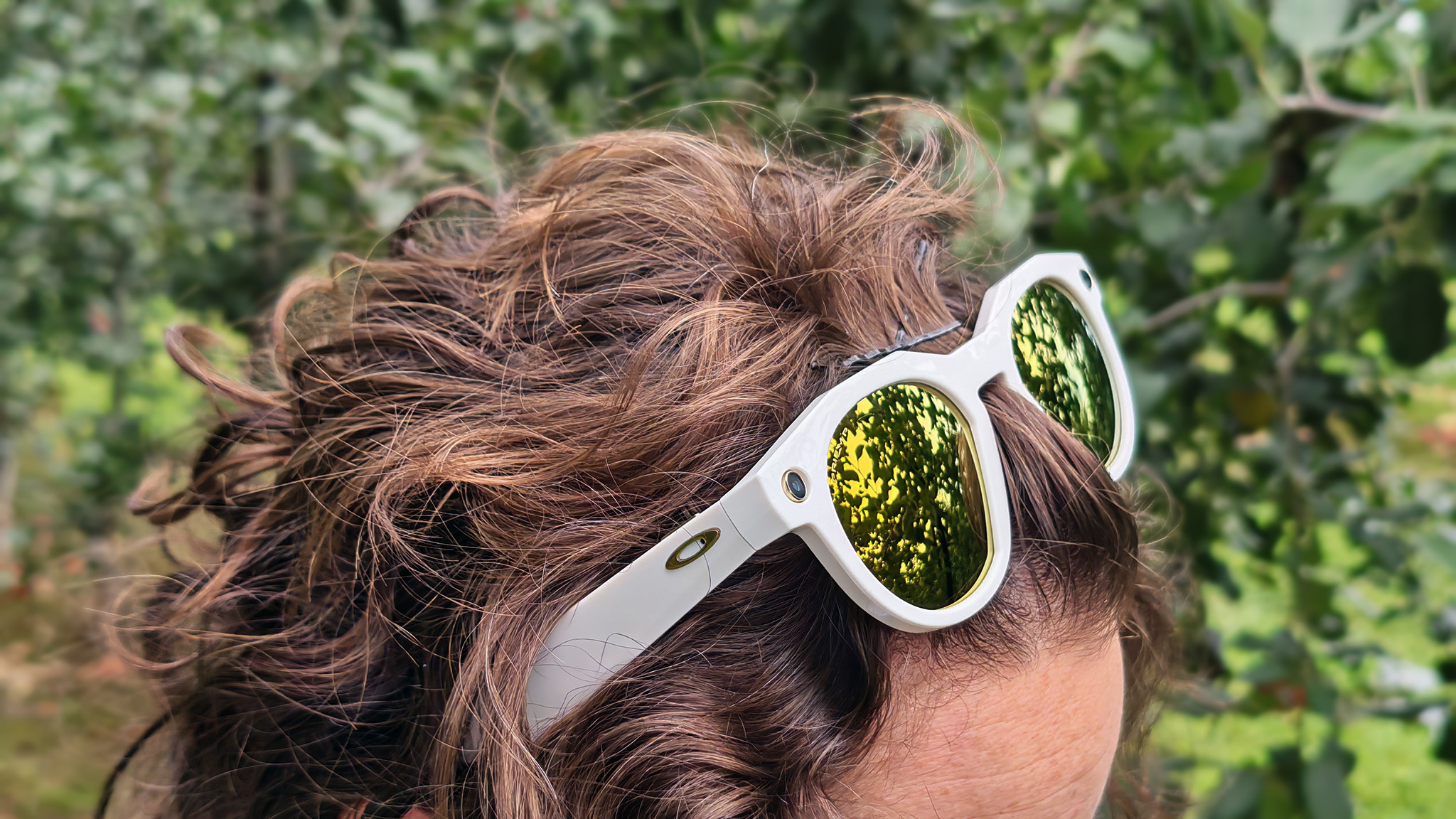 A woman wearing a pair of limited edition warm white Oakley Meta HSTN smart glasses on her head.