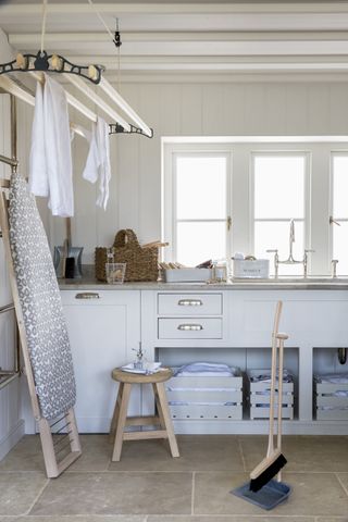 Utility room storage ideas showing a bright and airy utility room with a clothes dryer hung from the ceiling and cabinet storage