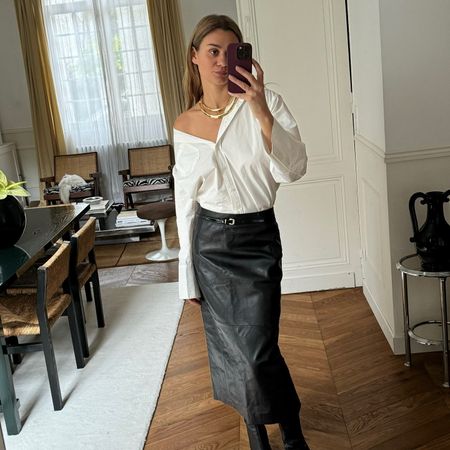 French fashion influencer @annelauremais wearing a chic outfit featuring staple Parisian fashion items for 2025, including an on-trend leather skirt and skinny belt.