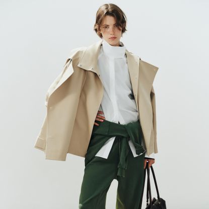 a Zara model wearing a cropped trench coat, white button down shirt and green joggers