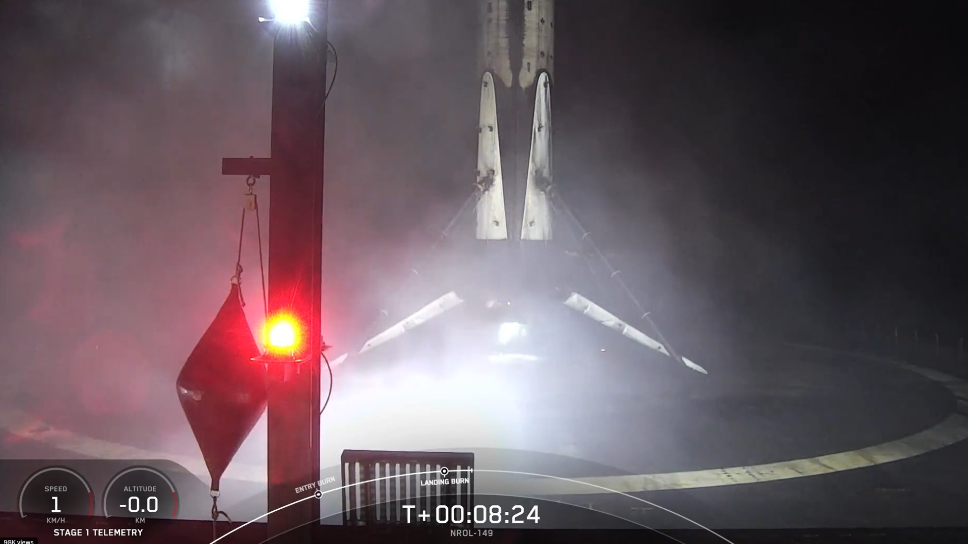 a soot-covered white rocket lands upright on four triangular legs on top of a flat-top barge at sea