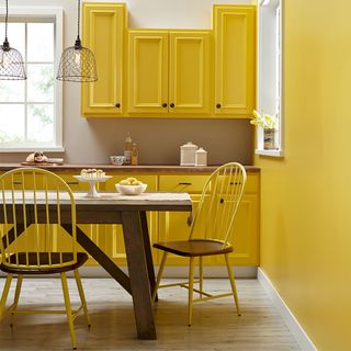 yellow kitchen with cabinets and dining table