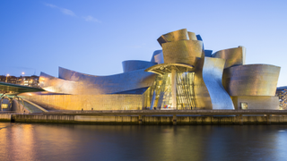 The Guggenheim Bilbao at nightfall viewed from across the river.