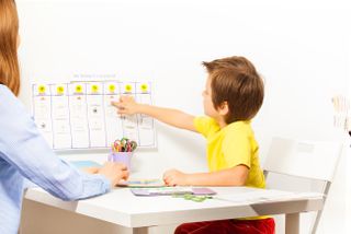 child pointing to activity planner on wall