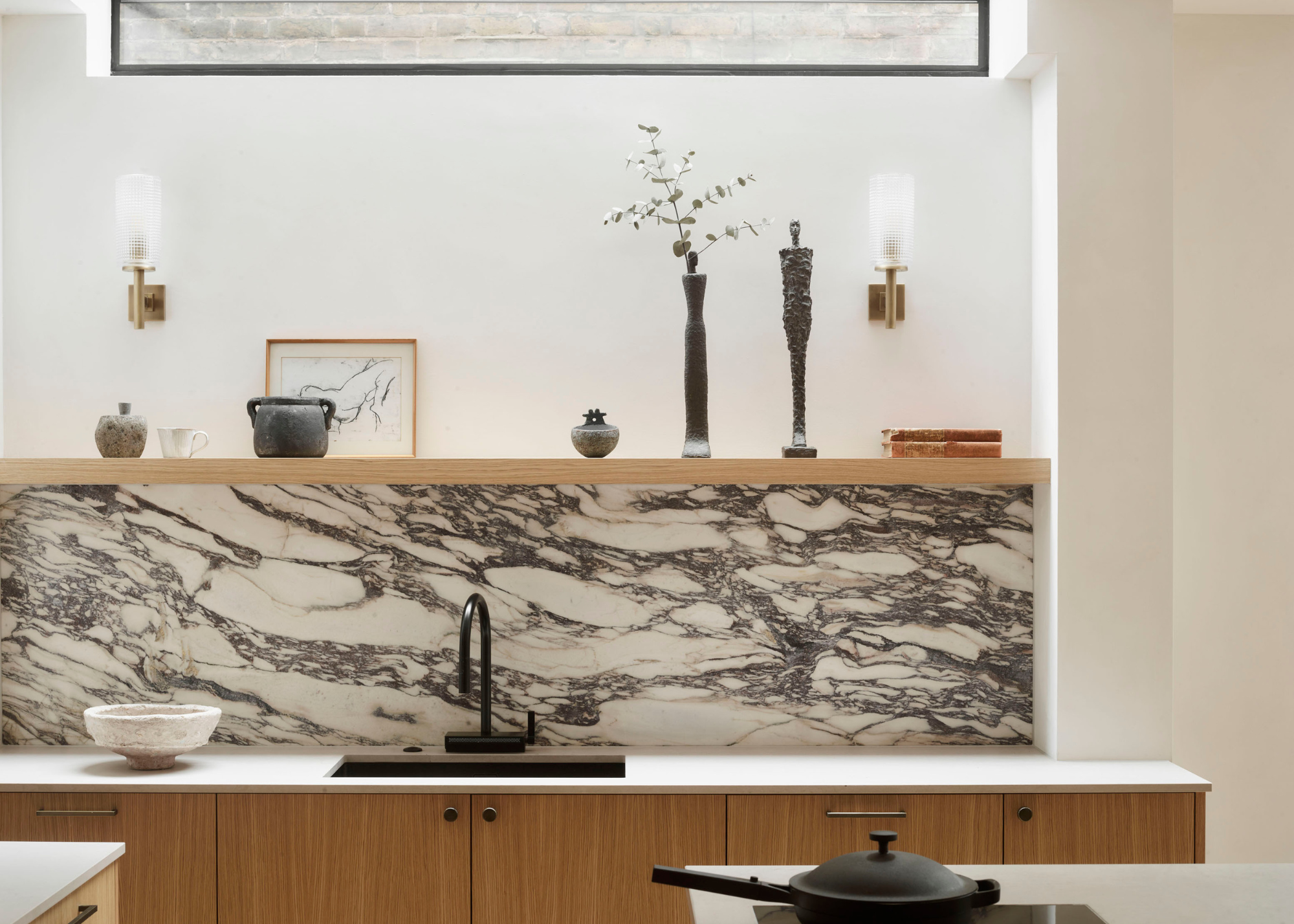 modern kitchen with marble splashback wooden cabinetry and open shelving with display pieces