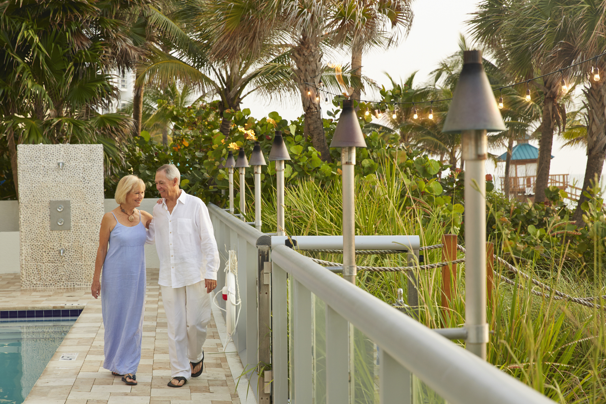 Older Caucasian couple walking near swimming pool