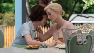 A still from the movie Mother's Instinct showing Jessica Chastain as Alice and Anne Hathaway as Céline, embracing at a table