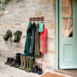 stone wall with cloths on hook and shoes