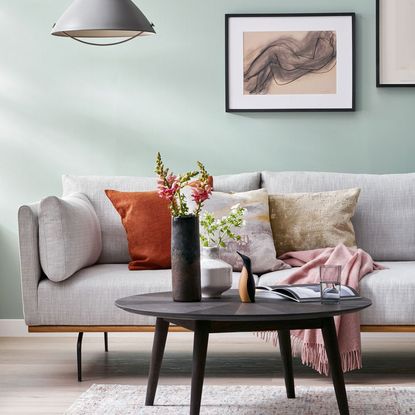living room with teal colour wall grey sofa and colourful cushions
