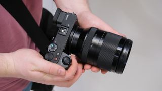 Sony FE 24-240mm lens attached to a Sony camera held in a pair of hands