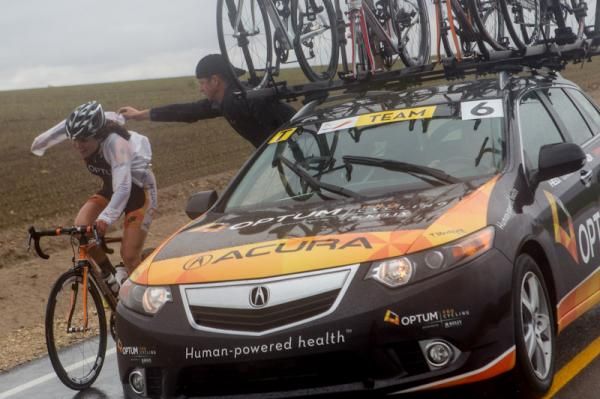 Joelle Numainville (Optum) gets some help putting on her rainy jacket.
