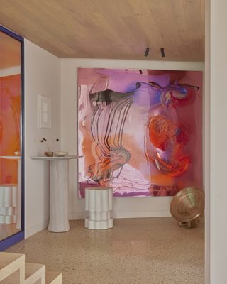 modern home foyer with timber ceiling, tiled floor, bright artwork with two pedestal tables