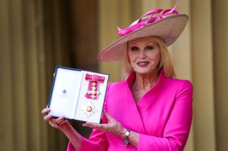 Dame Joanna Lumley poses with her medal and insignia after she was appointed a Dame Commander of the Order of the British Empire (DBE) for services to drama, entertainment and charity at a investiture ceremony at Buckingham Palace,