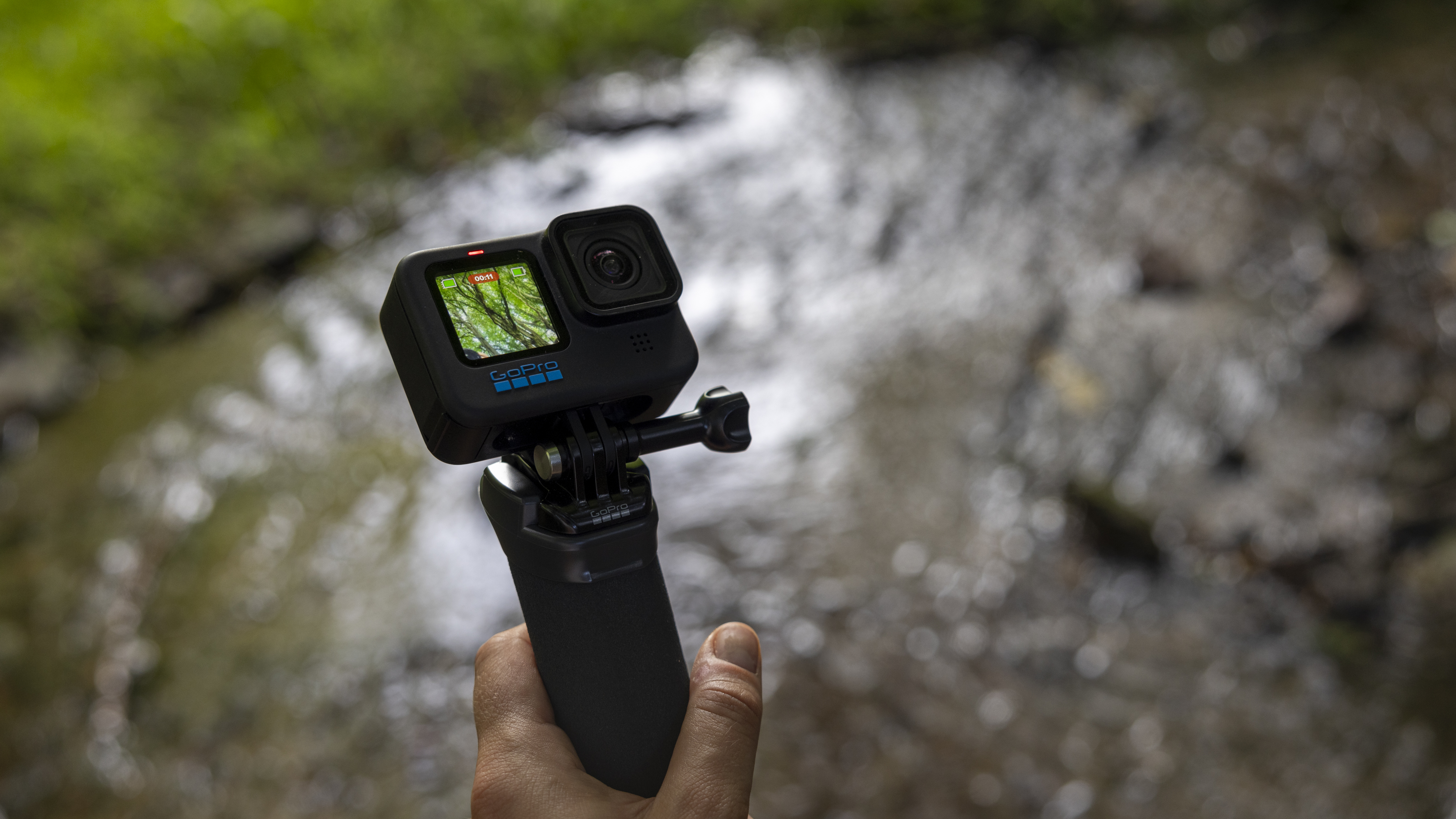 A GoPro Hero 10 Black on a floaty handler in front of a river