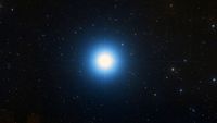 A bright blue star is pictured shining in a black sky surrounded by lesser stars.