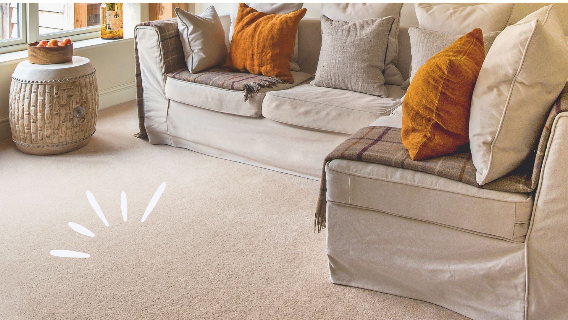 Neutral living room with cream carpet and cream sofa with burnt orange cushions
