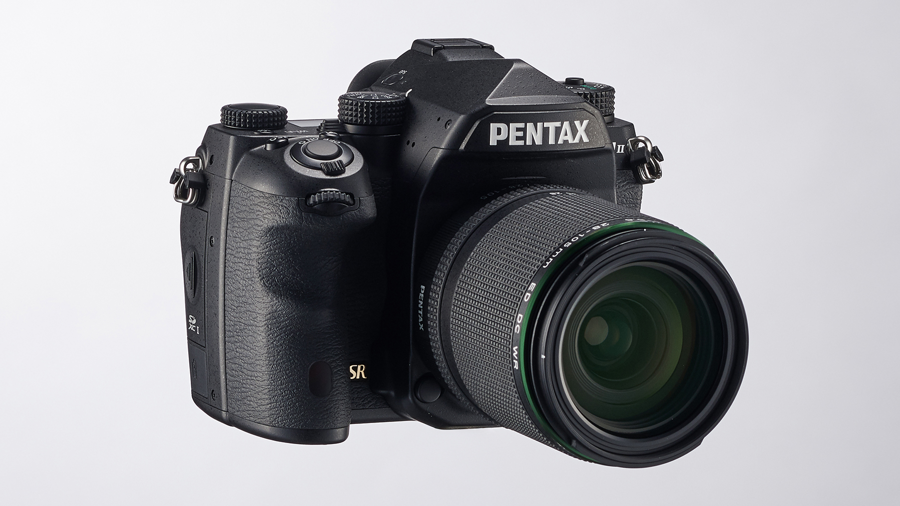 Black Pentax K-1 Mark II DSLR camera with zoom lens mounted on a small metal clamp against a plain white background