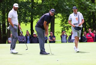 Phil Mickelson putts whilst Dustin Johnson looks on