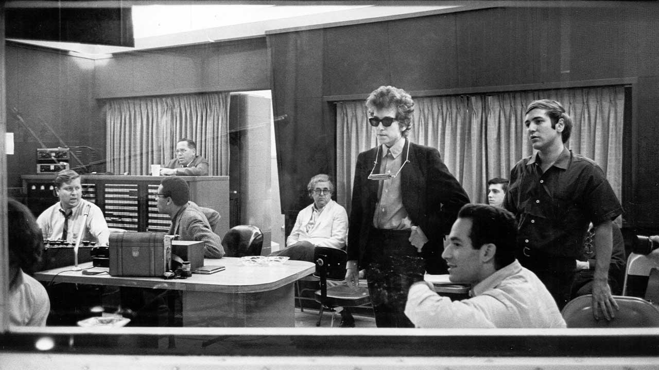 Bob Dylan and manager Albert Grossman listen back to the recordings of Highway 61 Revisited surrounded by engineers and other listeners at Columbia's Studio A in the summer of 1965 in New York City
