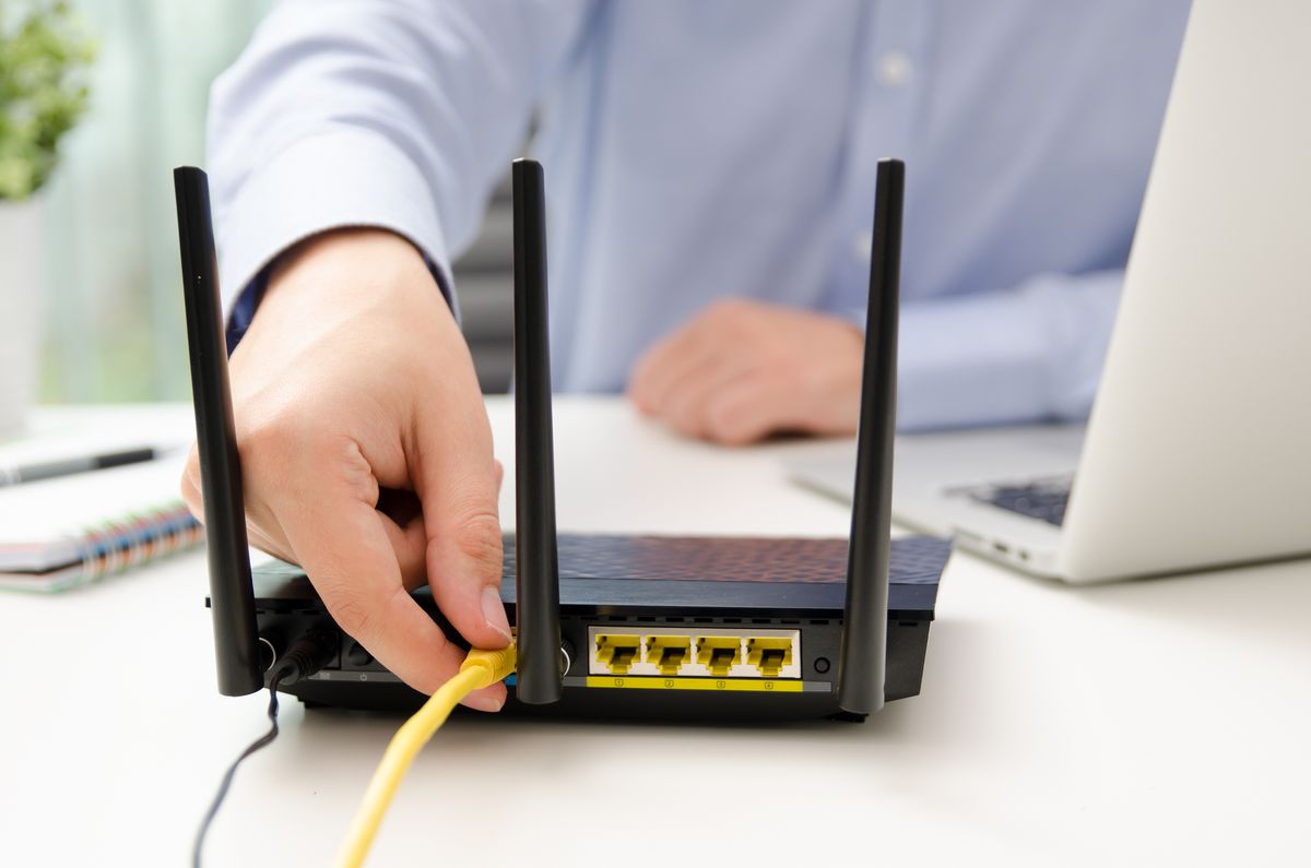 Man plugging Ethernet cable into a router