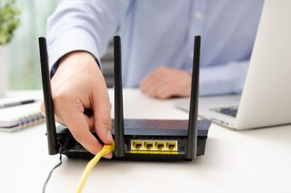 Man plugging Ethernet cable into a router