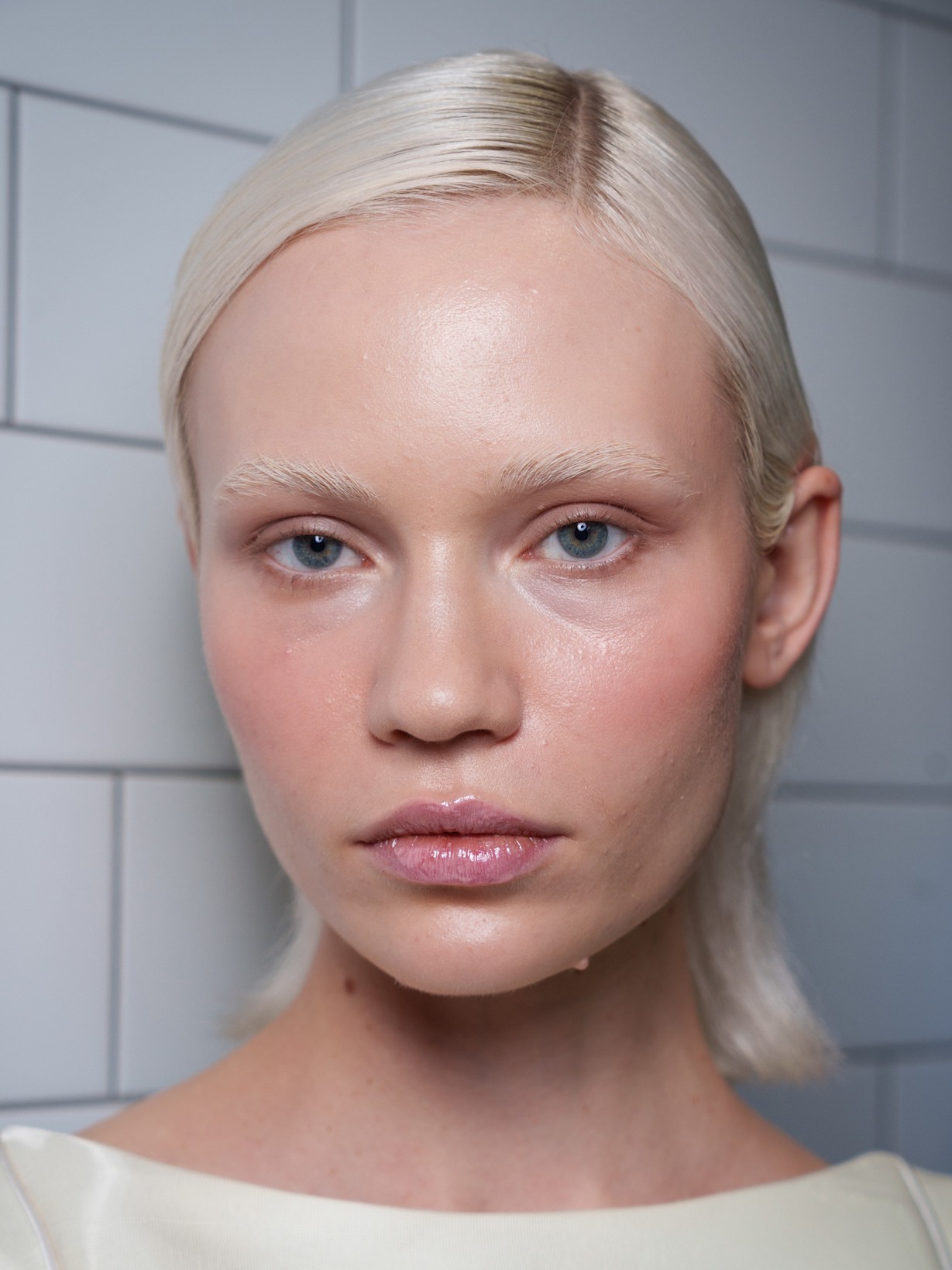 A model wearing white with a NYE-inspired makeup look thats glowy