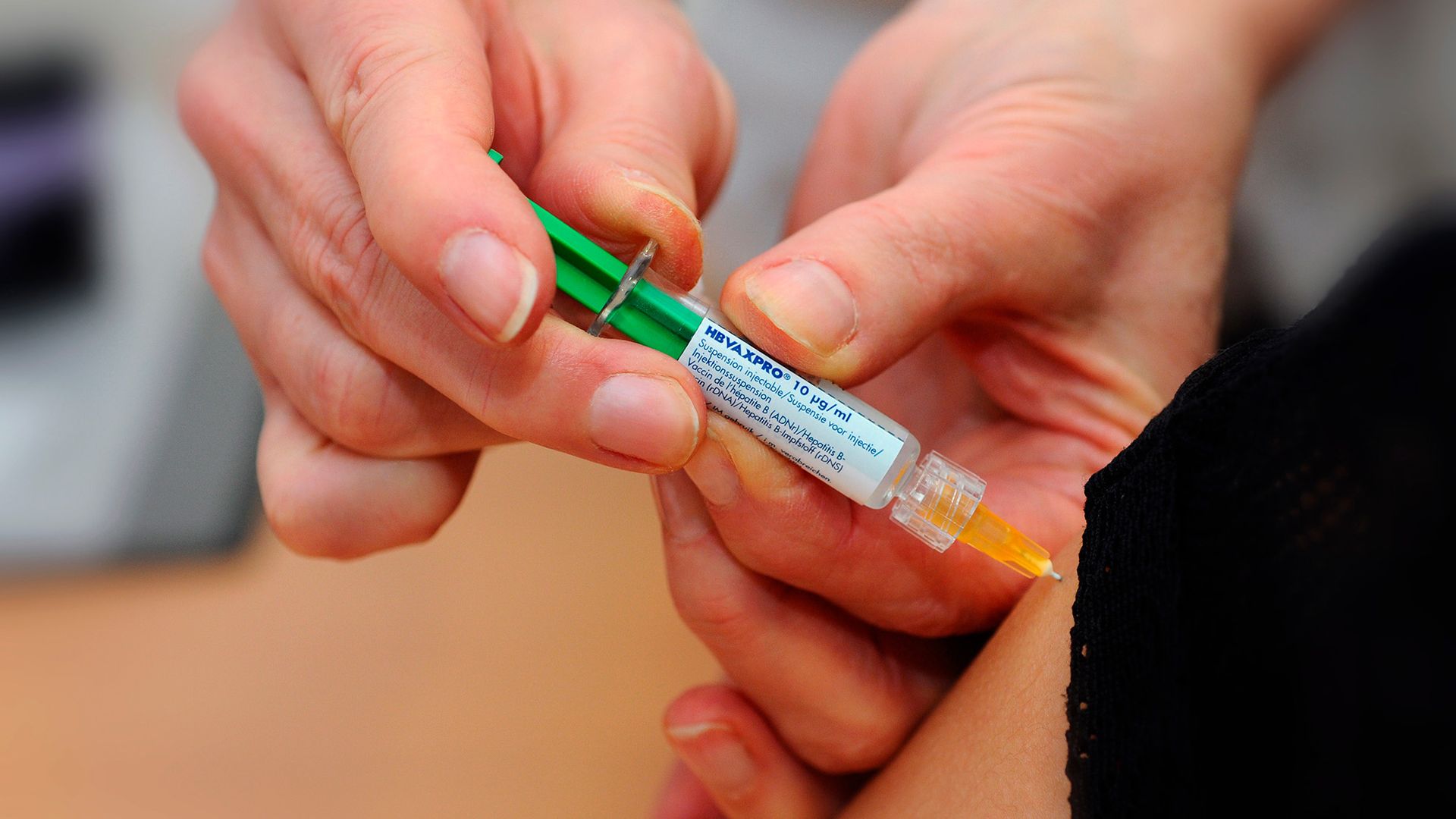 A close up of an orange liquid-filled syringe.