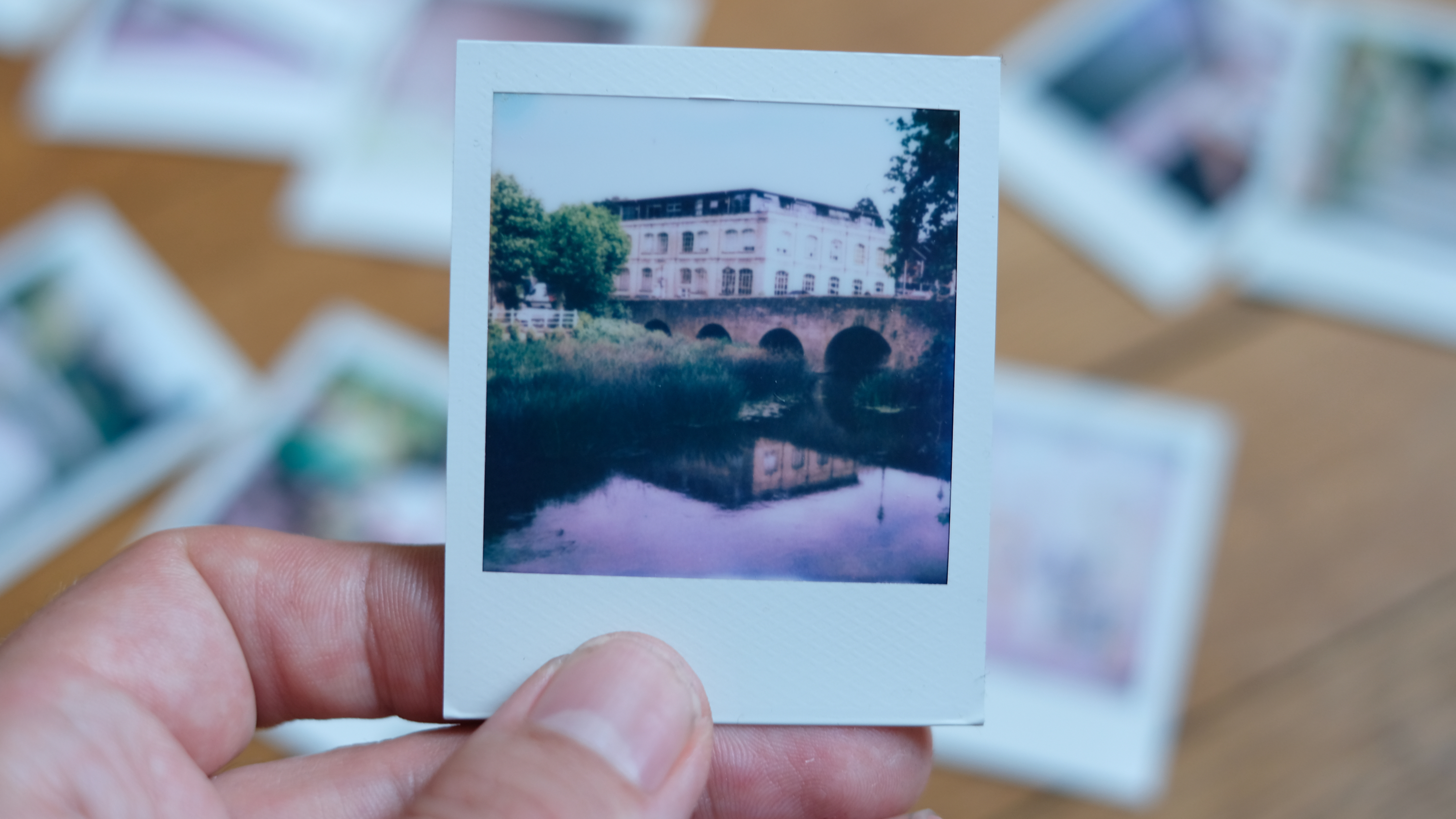 Photograph of prints made with Polaroid Go Gen 3, showing a riverside scene reflecting a bridge