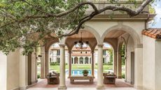 Loggia courtyard with arched doorways and swimming pool and terracotta tiling with large curved tree