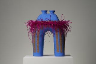 Colourful vase shaped like binoculars, with pink raffia frill