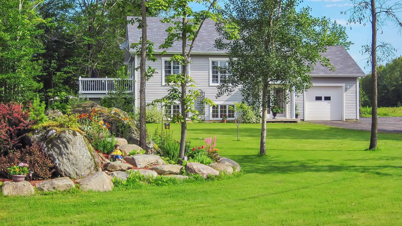 Street view of a picturesque country home with a large landscaped front yard 