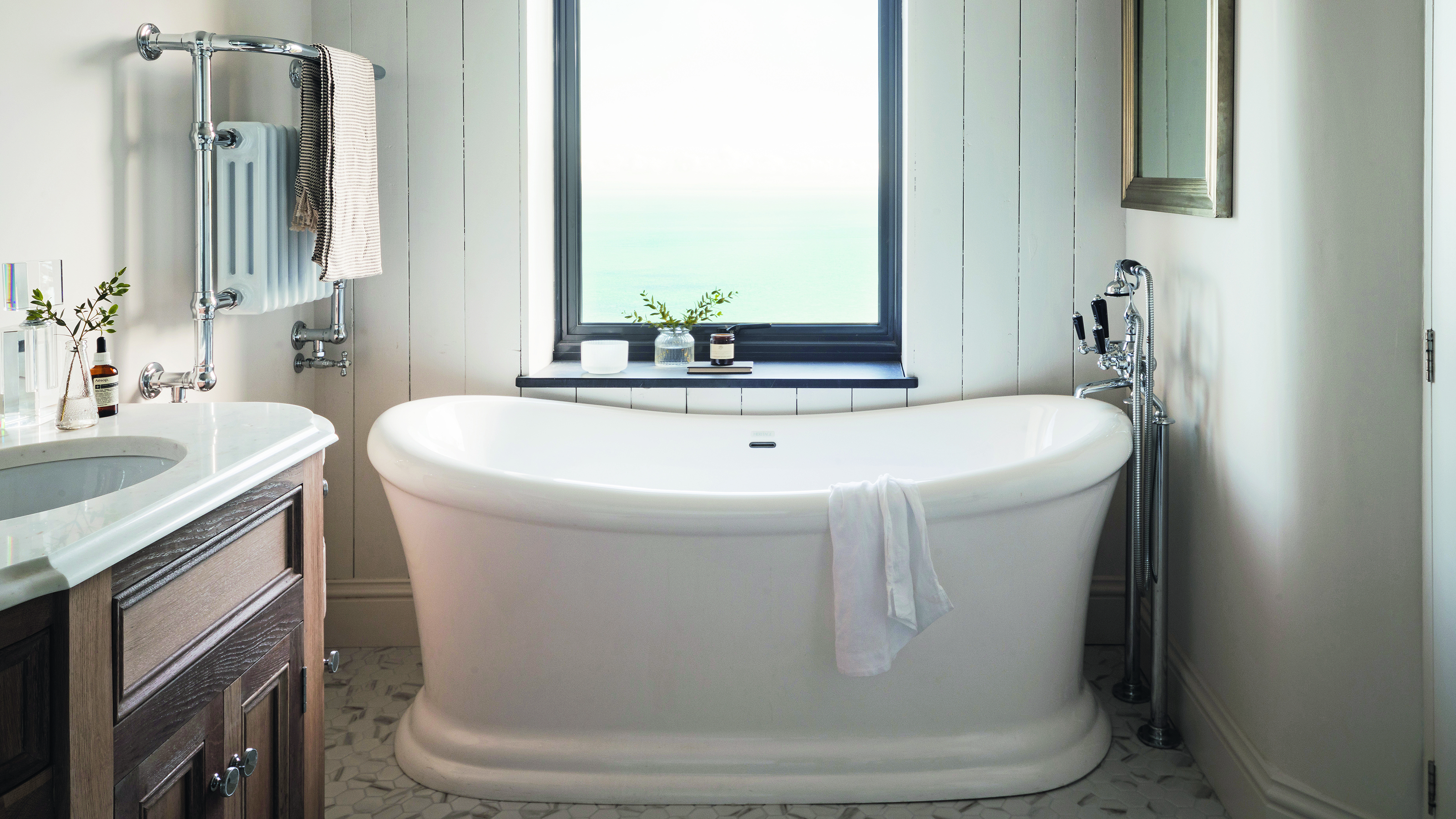 Coastal bahtroom with white bath and sea view from window