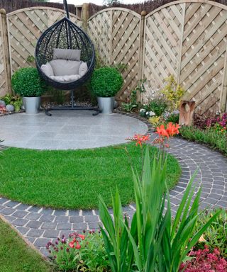 circular paved patio with circular lawn and hanging chair