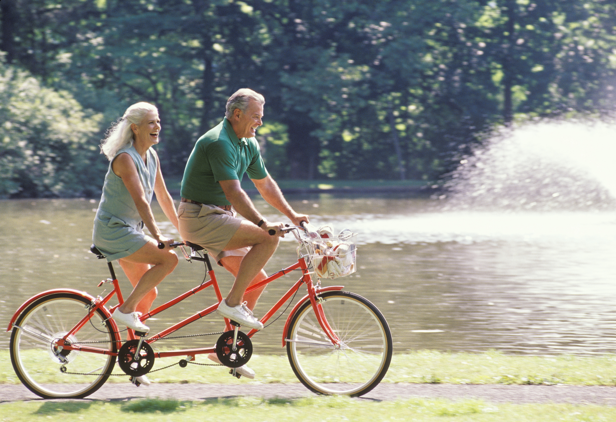 Mature couple riding bicycle for two, side view