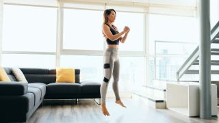 Woman performs jump squat exercise in her home