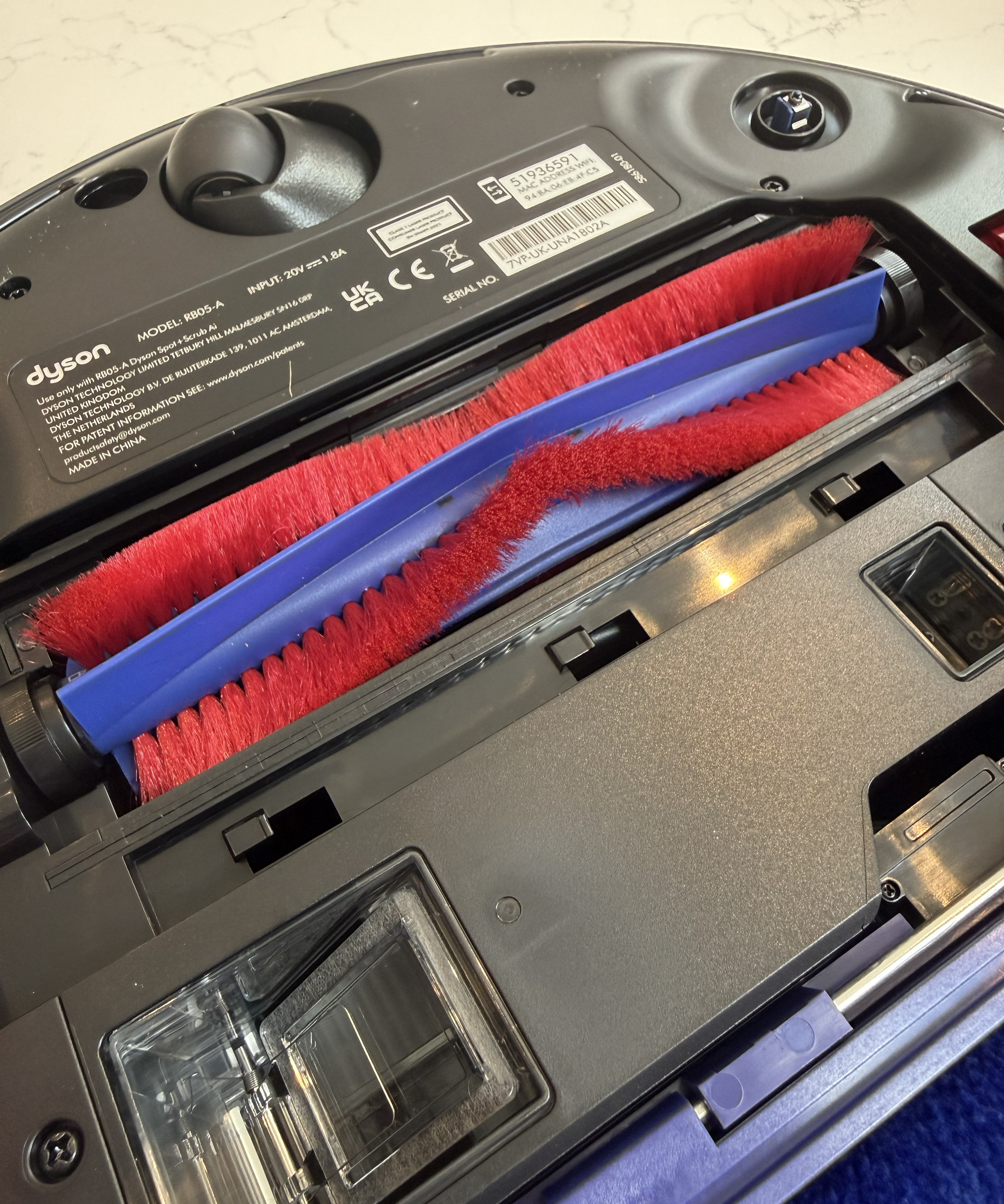 Close-up of the Dyson Spot+Scrub Ai underside showing the red brush bar in its housing