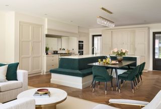 an open plan cream kitchen with a green banquette seating around an island